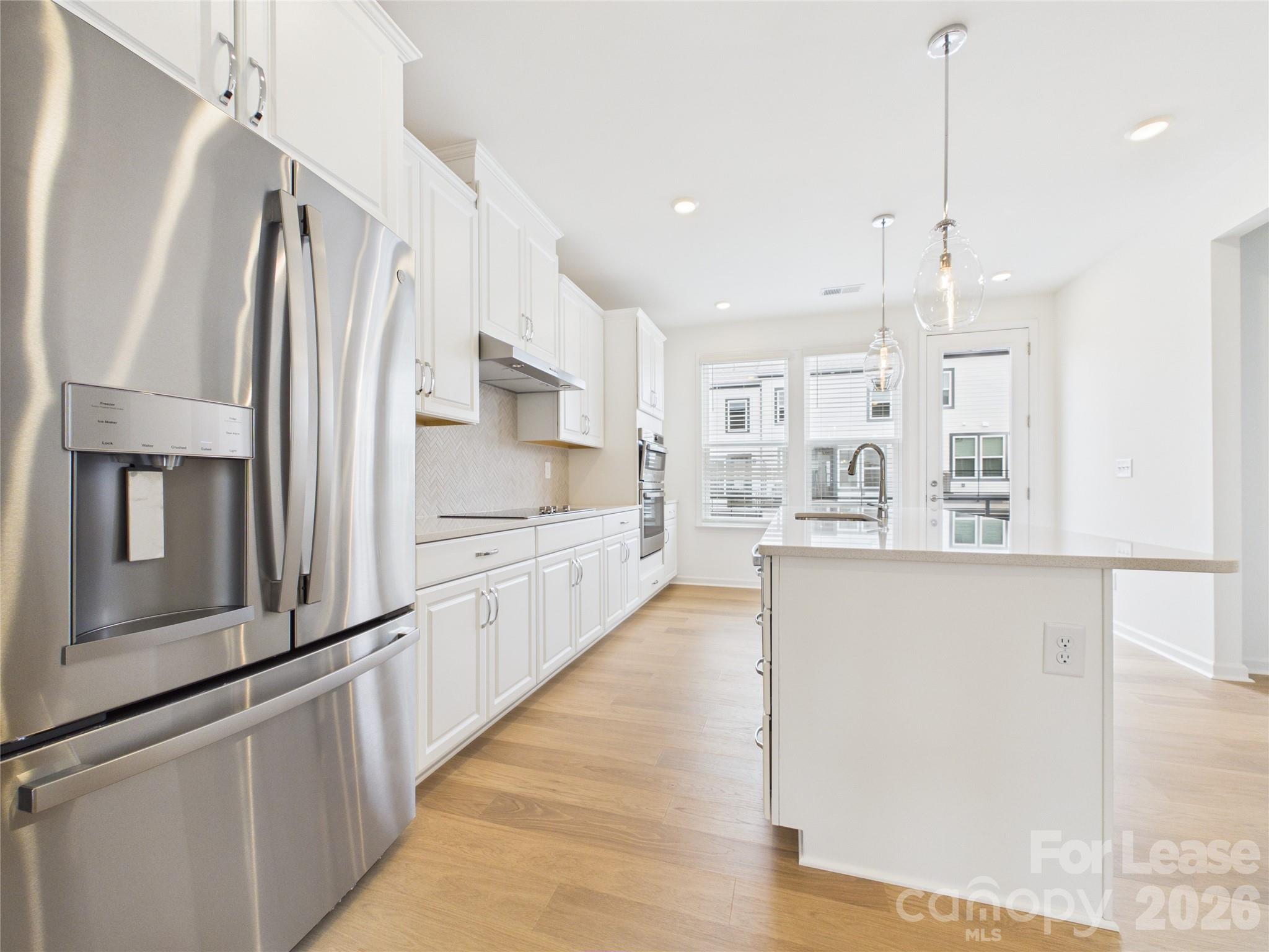 3013 Rexton Lane Charlotte, NC 28262 - Photo 4 of 27 a kitchen with stainless steel appliances a refrigerator sink and white cabinets