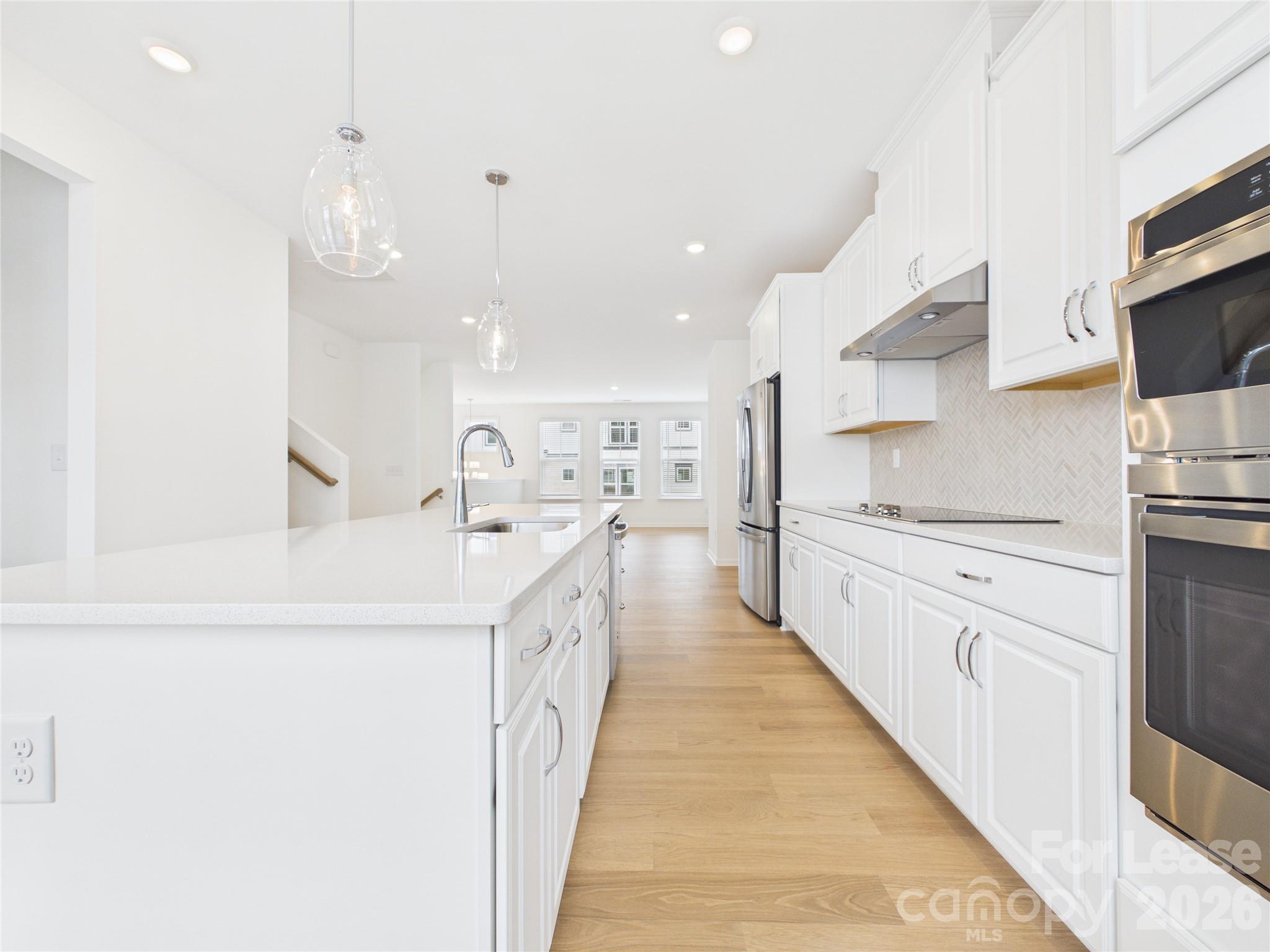 3013 Rexton Lane Charlotte, NC 28262 - Photo 6 of 27 a large white kitchen with kitchen island a sink a stove and a refrigerator
