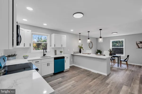 a large white kitchen with lots of counter space and wooden floor