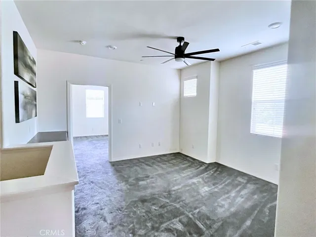 a view of an empty room with window and a ceiling fan