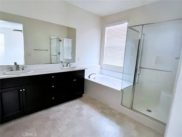 a spacious bathroom with a double vanity sink a mirror and a shower