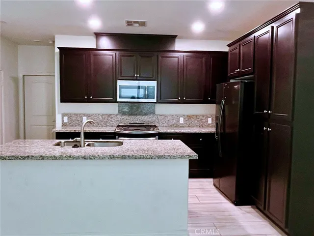 a kitchen with stainless steel appliances granite countertop a refrigerator and a sink