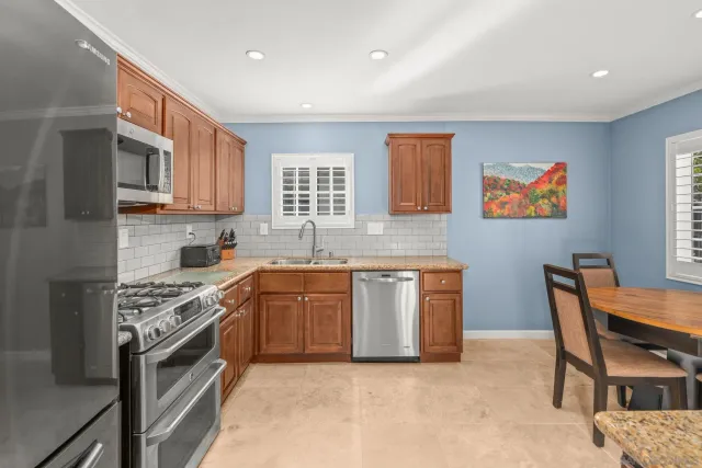 a kitchen with stainless steel appliances granite countertop a stove top oven a sink a dining table and chairs