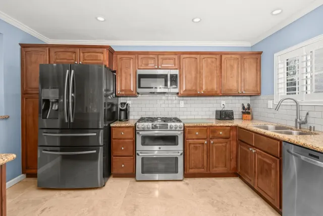 a kitchen with stainless steel appliances granite countertop a refrigerator and a stove top oven