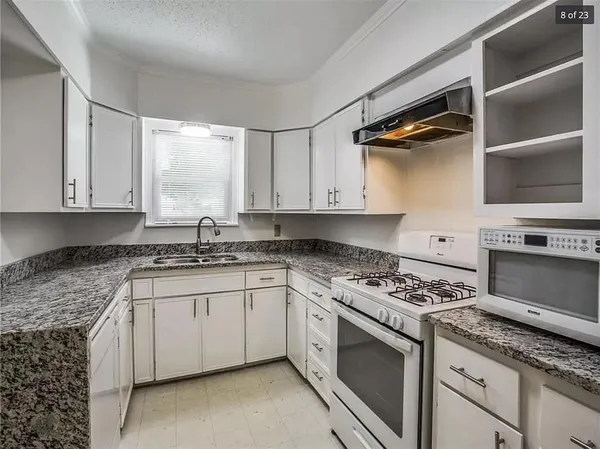a kitchen with granite countertop a stove sink and cabinets