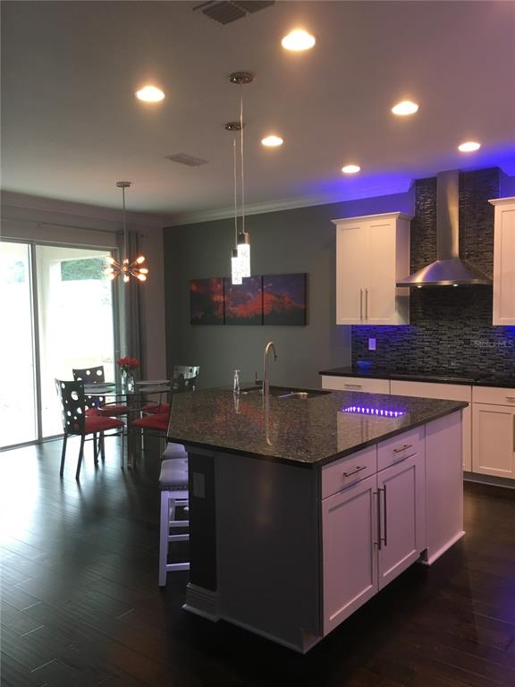2894 Sand Oak Loop Apopka, FL 32712 - Photo 22 of 69 a kitchen with kitchen island granite countertop a stove a sink a dining table and chairs