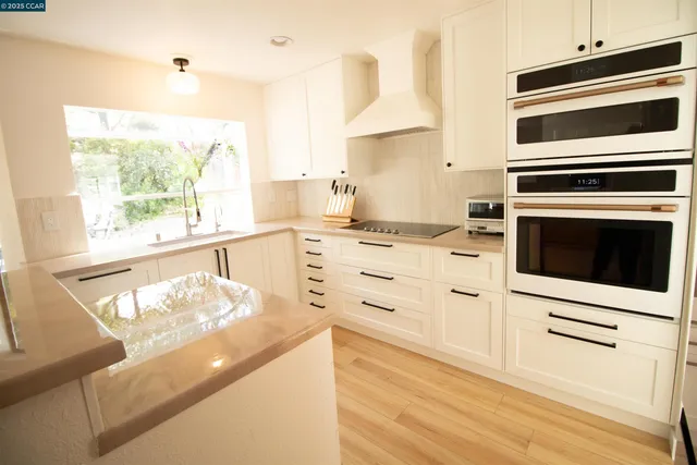 a kitchen with stainless steel appliances a stove and white cabinets