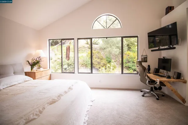 a bedroom with a large window and a flat screen tv