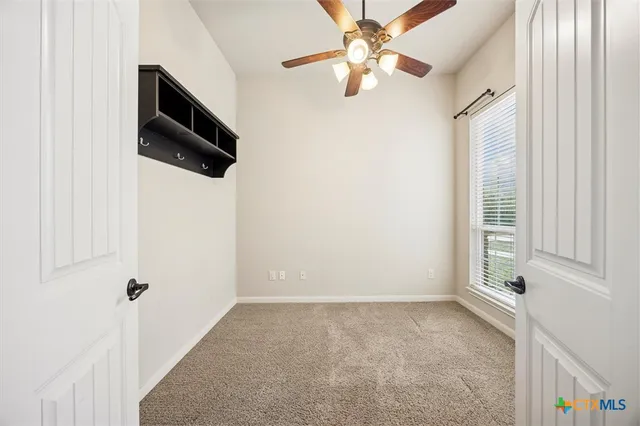 an empty room with windows and fan