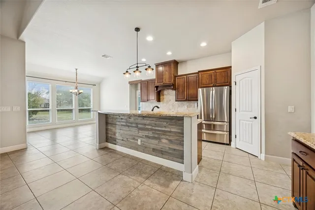 a view of kitchen with stainless steel appliances kitchen island granite countertop a sink and cabinets