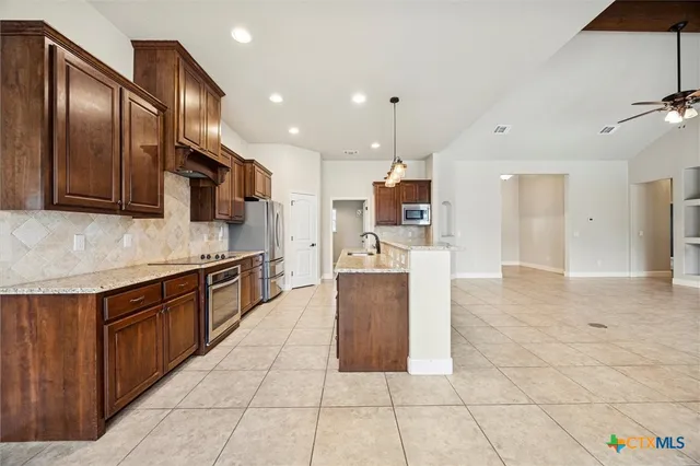 a large kitchen with stainless steel appliances kitchen island granite countertop a large counter top and a stove top oven