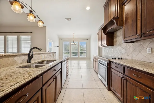 a large kitchen with granite countertop a sink and a stove