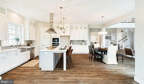 a kitchen with stainless steel appliances kitchen island granite countertop a stove a sink dishwasher and a dining table with wooden floor