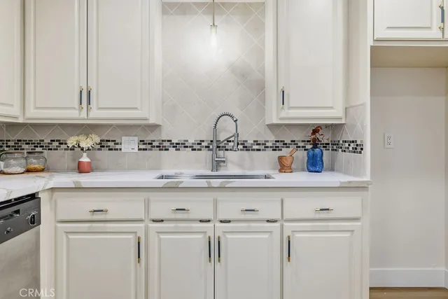 a kitchen with white cabinets and sink