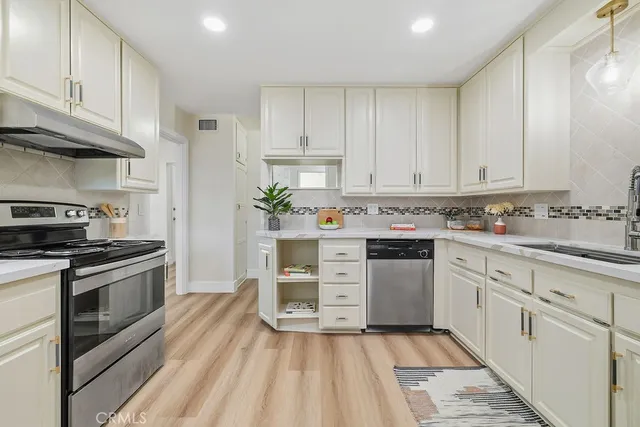 a kitchen with stainless steel appliances granite countertop a stove and white cabinets