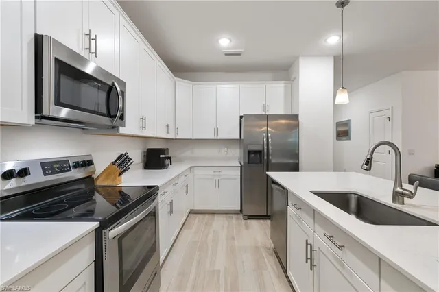 a kitchen with a sink white cabinets and stainless steel appliances