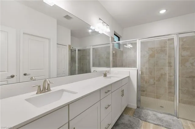 a bathroom with a double vanity sink mirror and shower