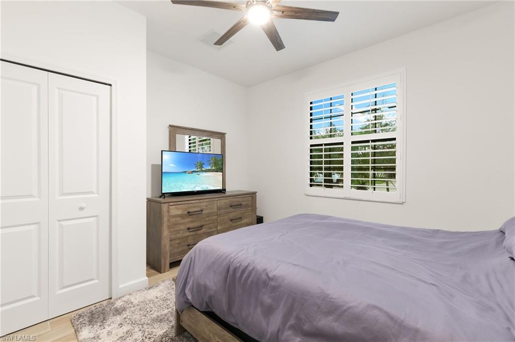 1473 Birdie Drive Naples, FL 34120 - Photo 23 of 50 a bedroom with a bed and a chandelier