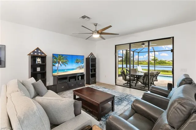 a living room with furniture a ceiling fan and a floor to ceiling window