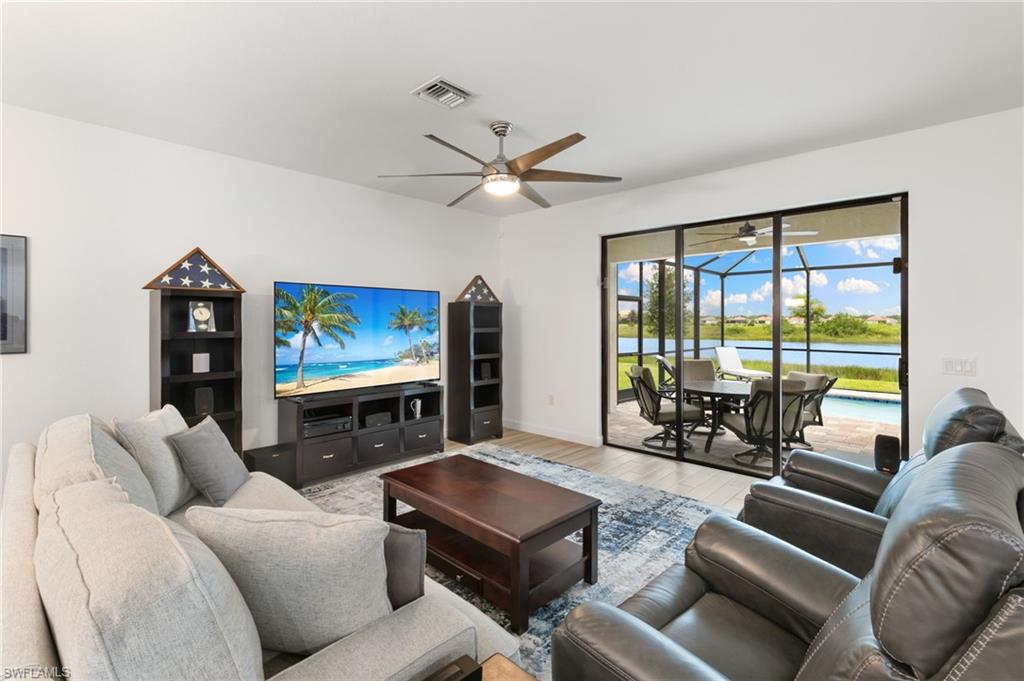 1473 Birdie Drive Naples, FL 34120 - Photo 7 of 50 a living room with furniture a ceiling fan and a floor to ceiling window