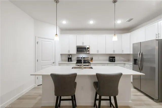 a kitchen with stainless steel appliances a refrigerator a stove a sink and chairs