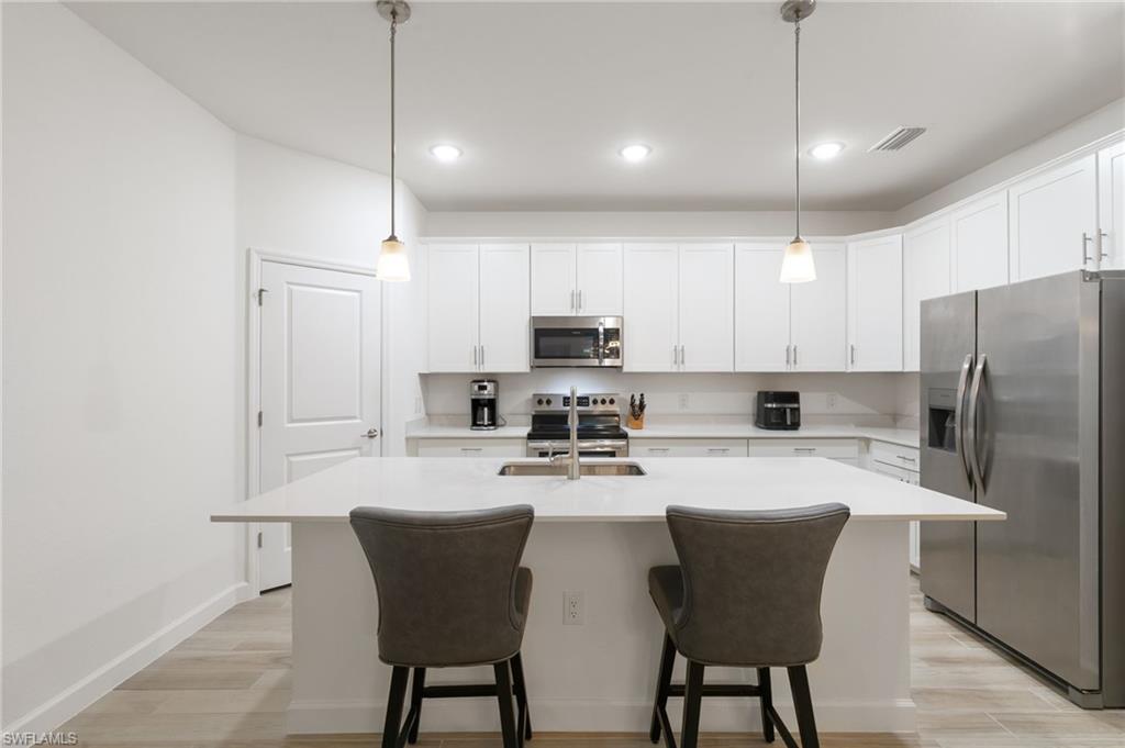 1473 Birdie Drive Naples, FL 34120 - Photo 10 of 50 a kitchen with stainless steel appliances a refrigerator a stove a sink and chairs