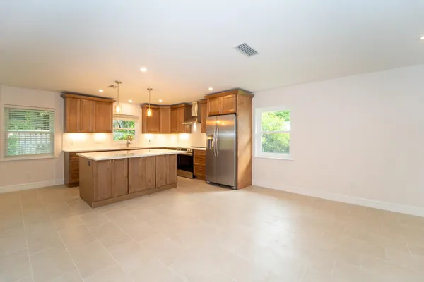 a kitchen with stainless steel appliances a sink a stove a refrigerator cabinets and a window