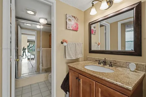 a bathroom with a granite countertop sink a mirror and a shower