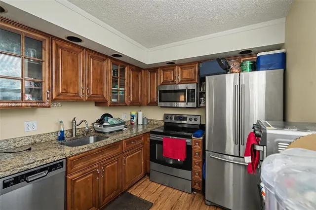 a kitchen with stainless steel appliances granite countertop a refrigerator sink and stove