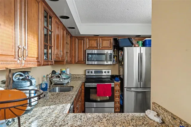 a kitchen with stainless steel appliances granite countertop a refrigerator stove and sink