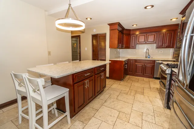 a kitchen with stainless steel appliances granite countertop a stove a sink a oven with a dining table and chairs