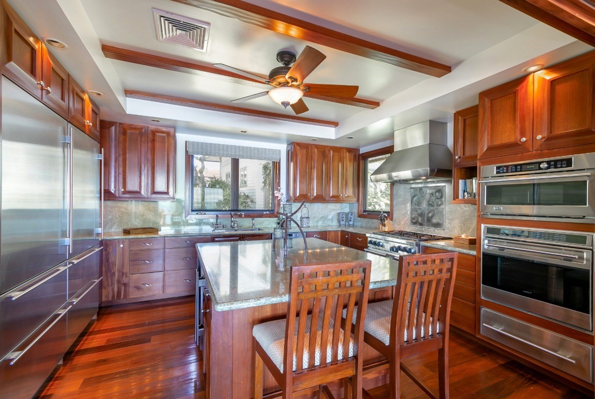 1871 Pe'e Road, Unit 1 Koloa, HI 96756 - Photo 5 of 24 a kitchen with stainless steel appliances granite countertop a stove top oven a sink a dining table and chairs with wooden floor