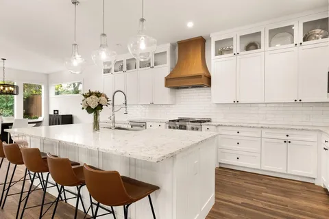 a large kitchen with kitchen island a stove a sink a center island and wooden floor