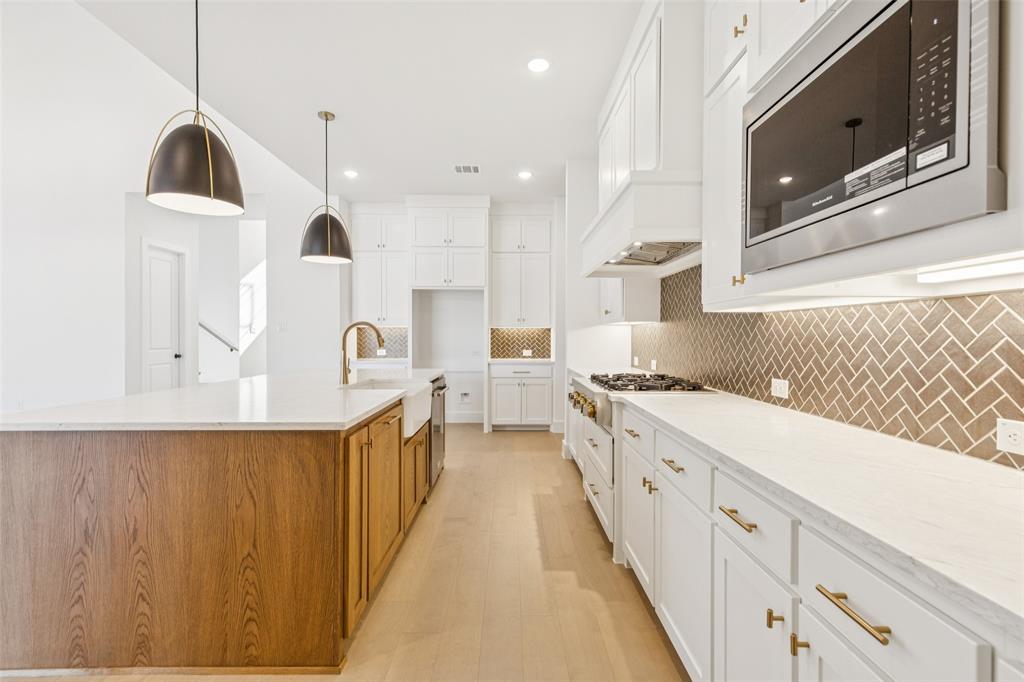 4050 Gambel Road Prosper, TX 75078 - Photo 9 of 23 Beautiful cabinetry, gorgeous counter tops and designer backsplash effortlessly blend with contemporary stainless steel to create a kitchen for the ages!