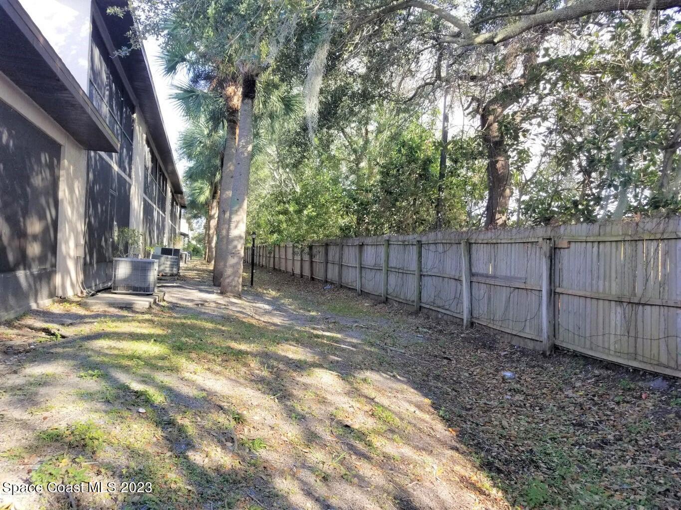 2939 Regency Drive Melbourne, FL 32935 - Photo 6 of 39 a view of a backyard with large trees and wooden fence