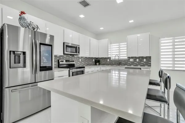 a kitchen with stainless steel appliances granite countertop a stove a refrigerator a kitchen island a table and chairs