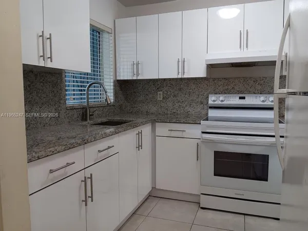 a kitchen with granite countertop white cabinets and white stainless steel appliances