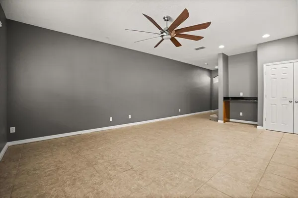 an empty room with staircase and a ceiling fan