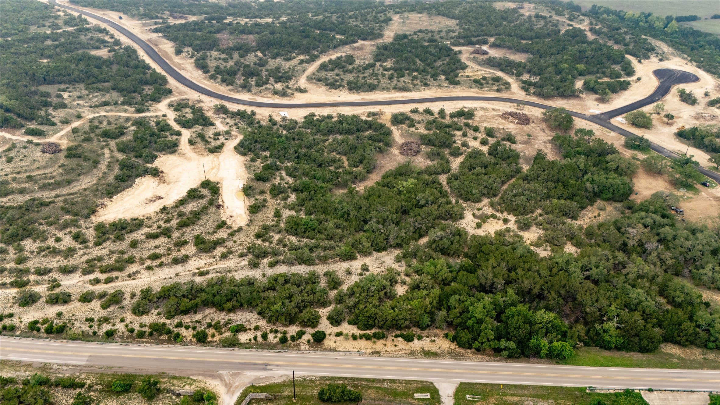 Lot 3 Ranch Road 165 Dripping Springs, TX 78620 - Photo 6 of 11 Aerial view of a sprawling land parcel featuring established paved roads, natural tree cover, and cleared areas
