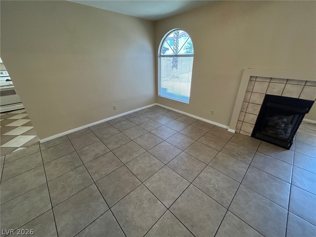 2806 Rungsted Street Las Vegas, NV 89142 - Photo 5 of 18 A corner fireplace adds warmth to this living space, featuring practical tile flooring and an arched window.