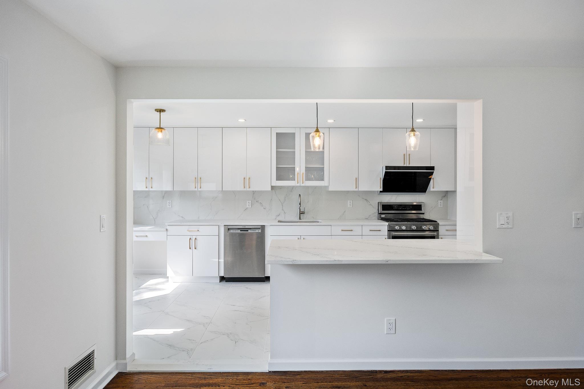 372 Heathcote Road Scarsdale, NY 10583 - Photo 5 of 20 Kitchen with glass insert cabinets, appliances with stainless steel finishes, white cabinets, light stone countertops, and backsplash