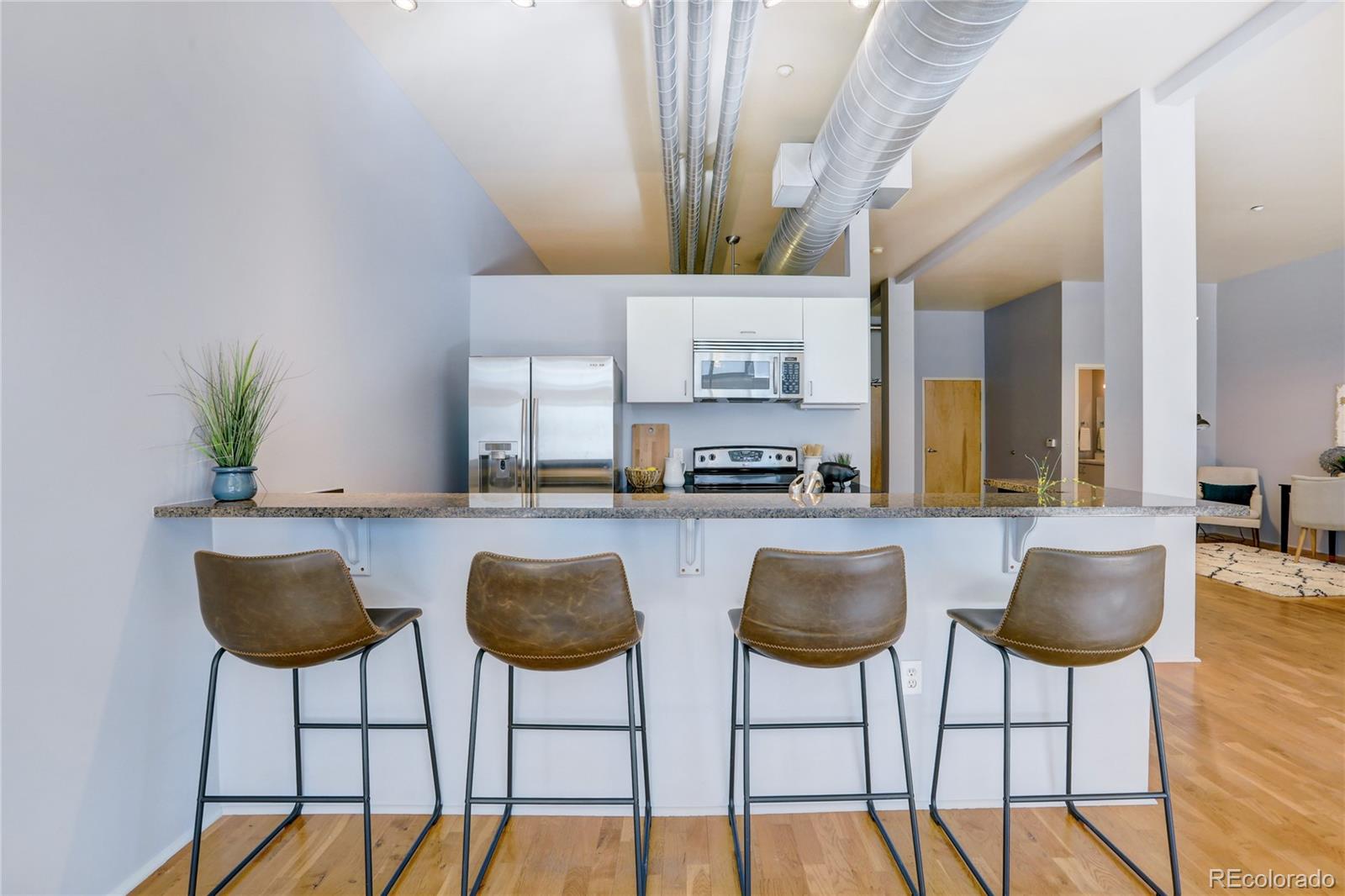 3100 Huron Street, Unit 2R Denver, CO 80202 - Photo 24 of 33 a kitchen with stainless steel appliances kitchen island a table and chairs in it