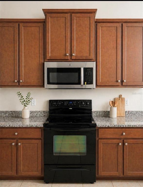 8253 Maritime Flag Street, Unit 109 Windermere, FL 34786 - Photo 11 of 23 a kitchen with granite countertop wood cabinets and stainless steel appliances