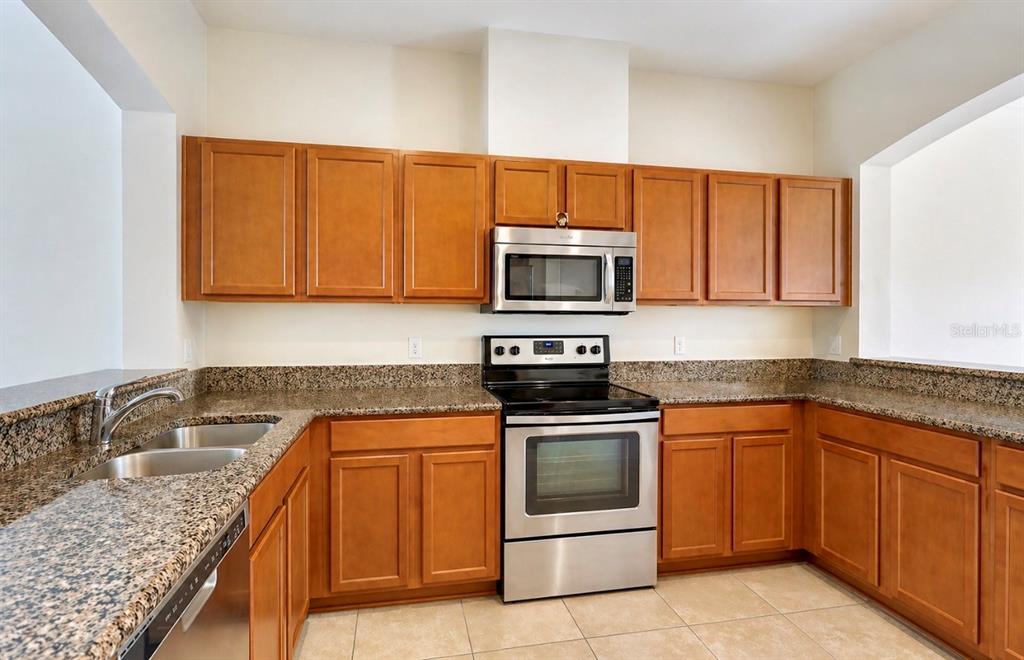 8253 Maritime Flag Street, Unit 109 Windermere, FL 34786 - Photo 6 of 23 a kitchen with granite countertop a sink stove and microwave