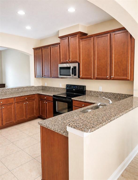 8253 Maritime Flag Street, Unit 109 Windermere, FL 34786 - Photo 7 of 23 a kitchen with granite countertop a stove a sink and a microwave
