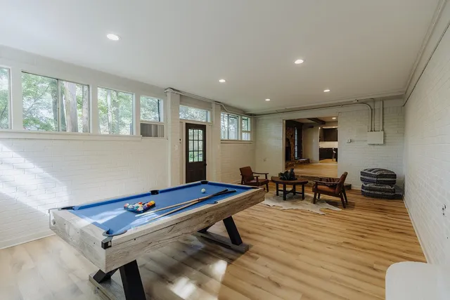 a living room with furniture pool table and windows