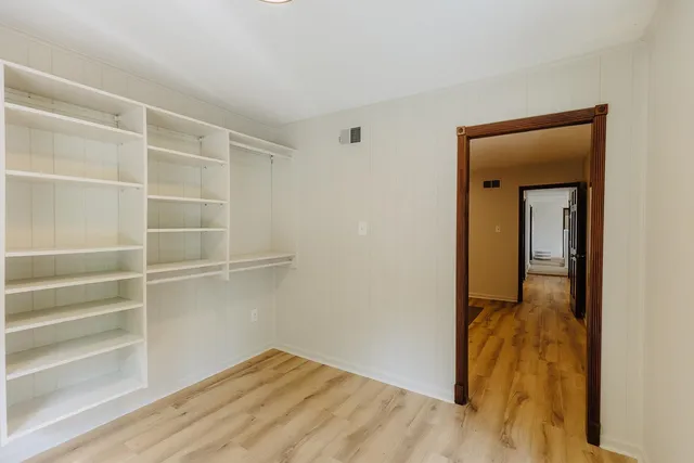 a view of a hallway with wooden floor and closet