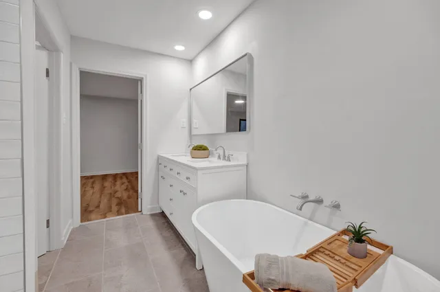 a bathroom with a tub sink and mirror