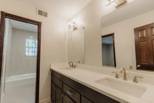 a bathroom with a double vanity sink a mirror and a