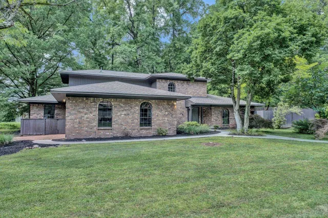 a front view of a house with a garden and trees